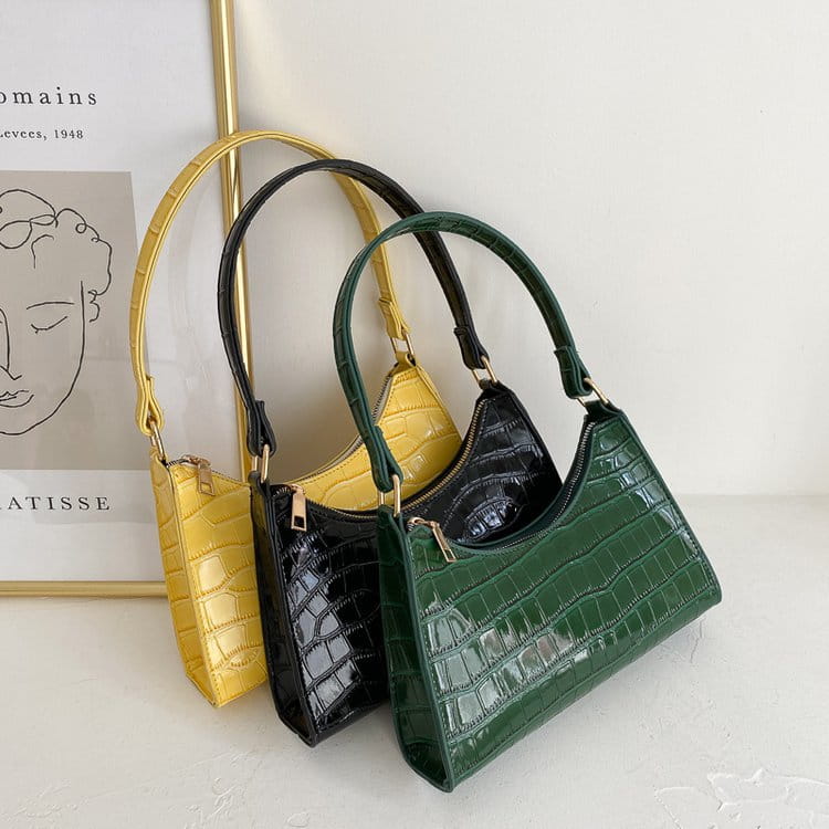 Three crocodile embossed pu leather crescent messenger bags in yellow black and green with glossy finishes.