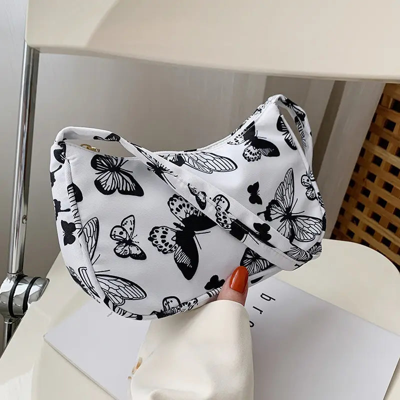 White canvas animal print underarm shoulder bag for women featuring a black butterfly print and an adjustable strap.