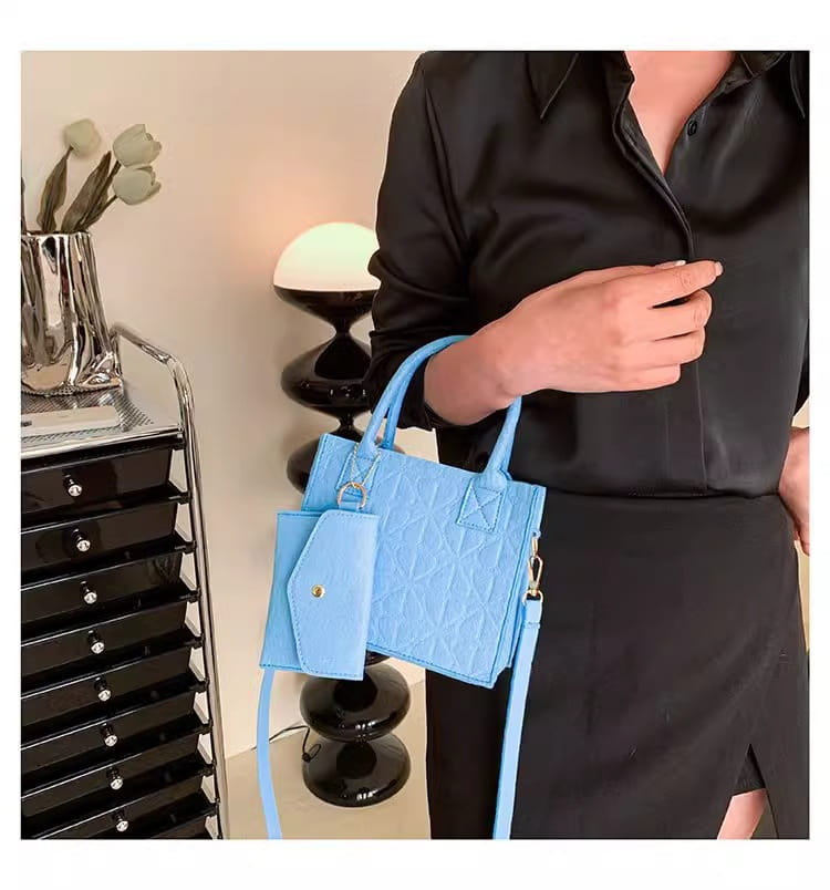 Hellblaue wattierte Filzhandtasche mit abnehmbarem, passendem Träger und einer kleinen, angebrachten Geldbörse als Teil eines Filzhandtaschen-Sets.