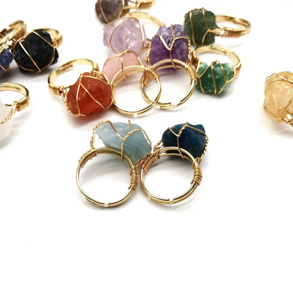 Handcrafted raw gemstone gold wire wrapped adjustable rings featuring colorful gemstones in purple green orange and blue hues.