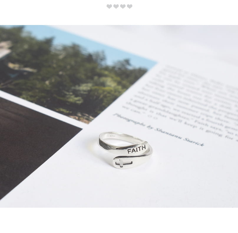 A sleek silver wrap-around ring with an adjustable band engraved with the word faith and a cross symbol.