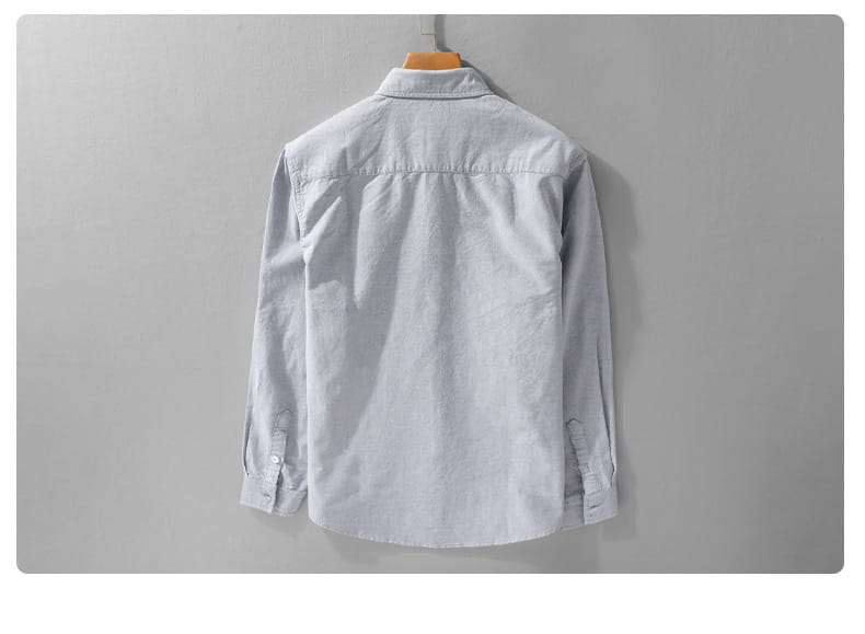 Herren-British-Style-gestreiftes Oxford-Baumwollhemd mit langem Arm in hellem Grau, auf einem hölzernen Kleiderbügel hängend.