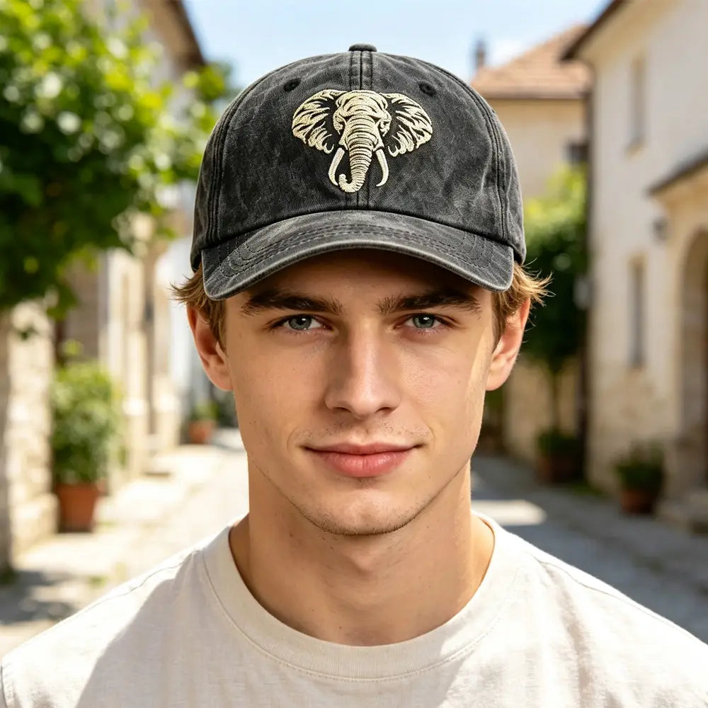 Dark gray distressed cotton baseball cap featuring a detailed cream-colored embroidered elephant design in a vintage washed style.