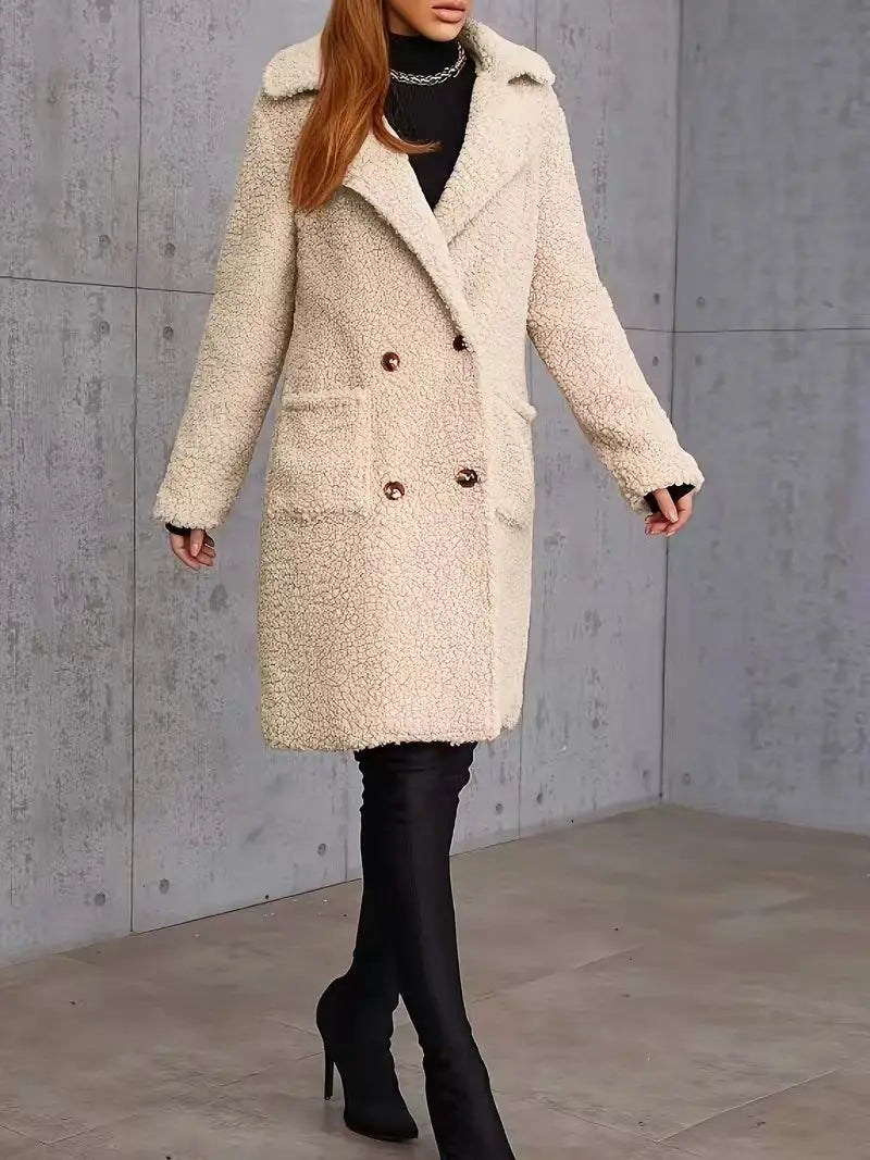 Manteau teddy mi-long doublé en polaire de couleur crème, présentant une texture moelleuse, une fermeture à double boutonnage à l’avant et des boutons à ton or