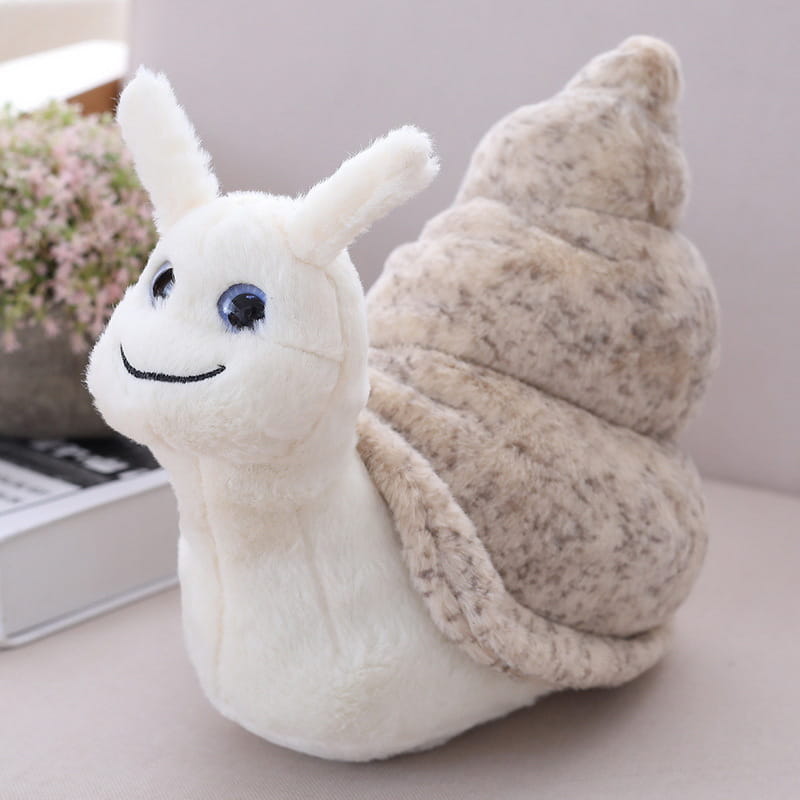A soft stuffed animal snail plush toy with a plush white body, textured beige shell, and embroidered blue eyes.