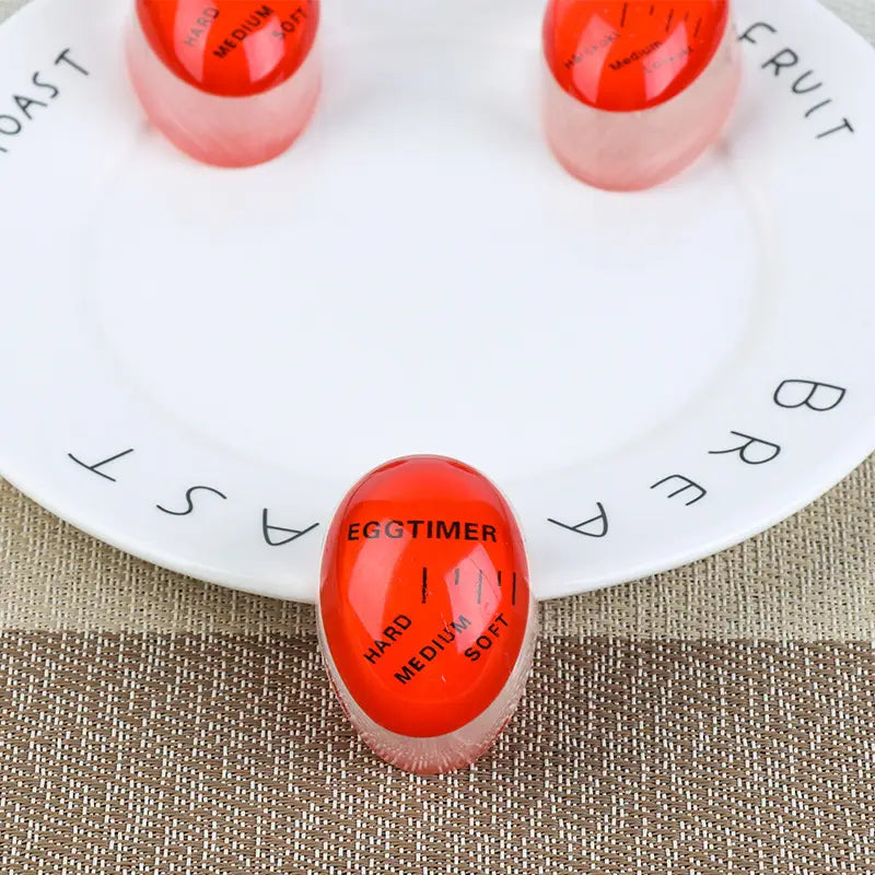Roter durchscheinender eiförmiger Timer mit schwarzer Beschriftung zur Anzeige der Einstellungen für hart, mittel und weich für die zeitliche Erfassung von Farbwechsel-Soft-Medium-Hardboiled-Eiern.