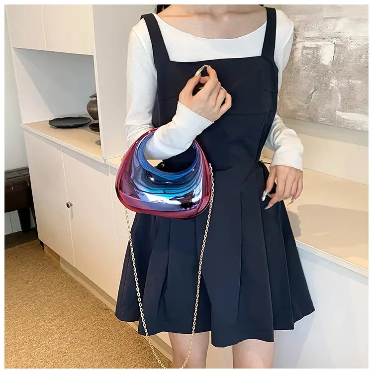 Acrylic gold chain handbag featuring a glossy iridescent metallic clutch with a curved asymmetrical shape and chain strap.