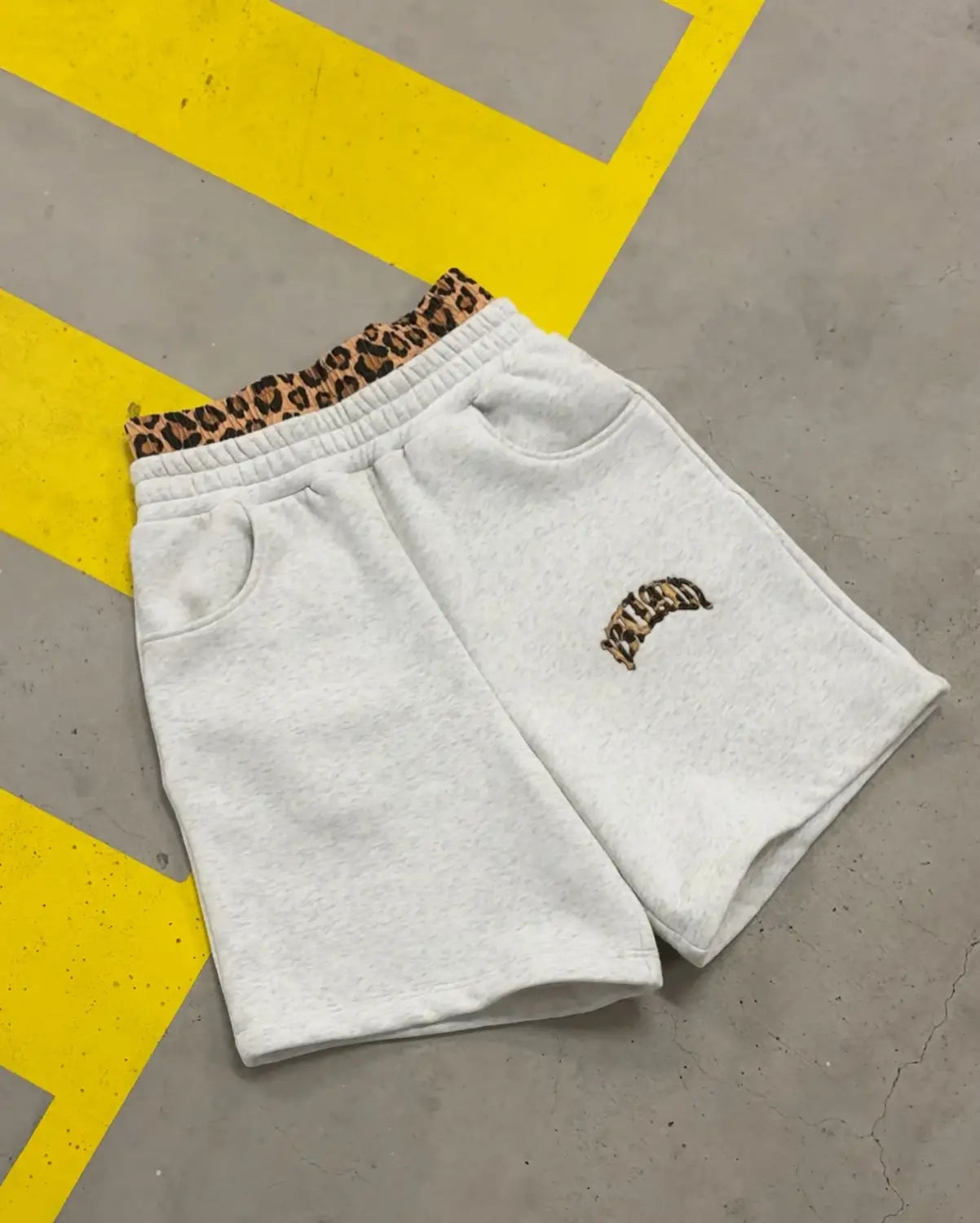 Shorts de sport blancs, issus de l’ensemble sweat à capuche et jogging à imprimé léopard, avec une ceinture élastique à imprimé léopard et un écusson brodé assorti sur la cuisse.