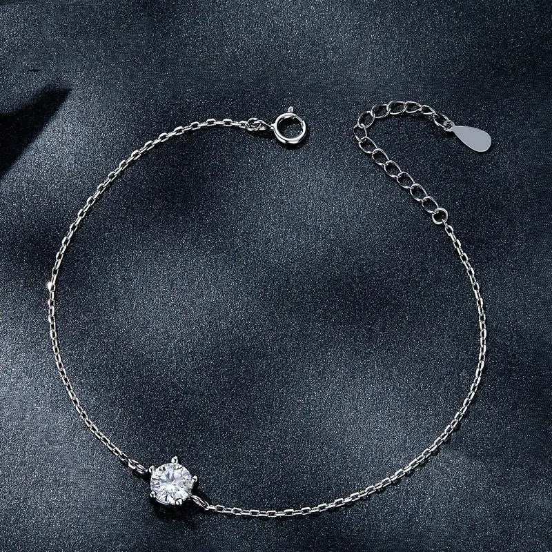 Silver chain bracelet featuring a single round-cut clear moissanite gemstone with an adjustable clasp and a small tag.