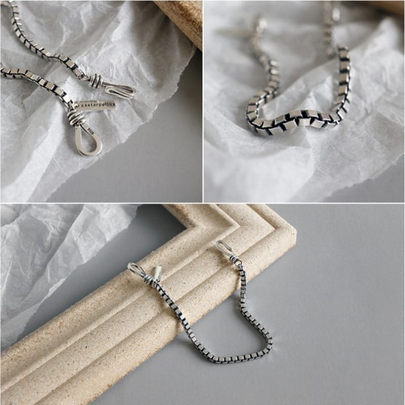 Vintage silver box chain cross bracelet featuring a silver-toned interlocking design and a small engraved brand tag.