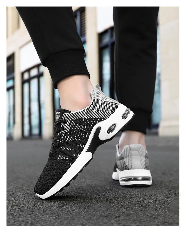 Baskets décontractées pour hommes en mesh flyknit à coussin d’air, en noir et gris, avec semelle intermédiaire blanche et unités d’amorti par coussin d’air transparentes.