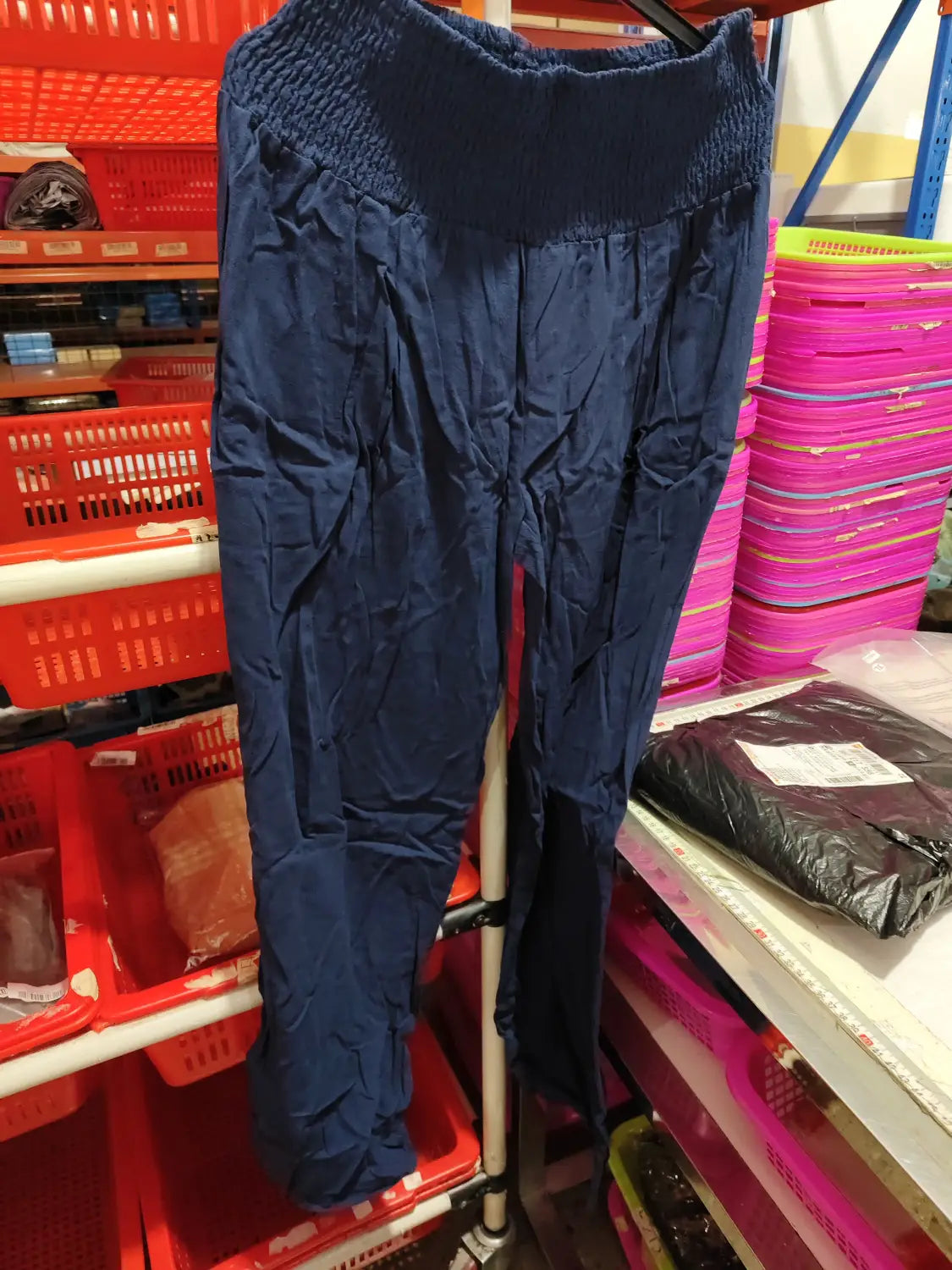 Navy blue smocked wide leg pants for women featuring a high waist with elastic band and smooth slightly wrinkled fabric with subtle pleats down the front.