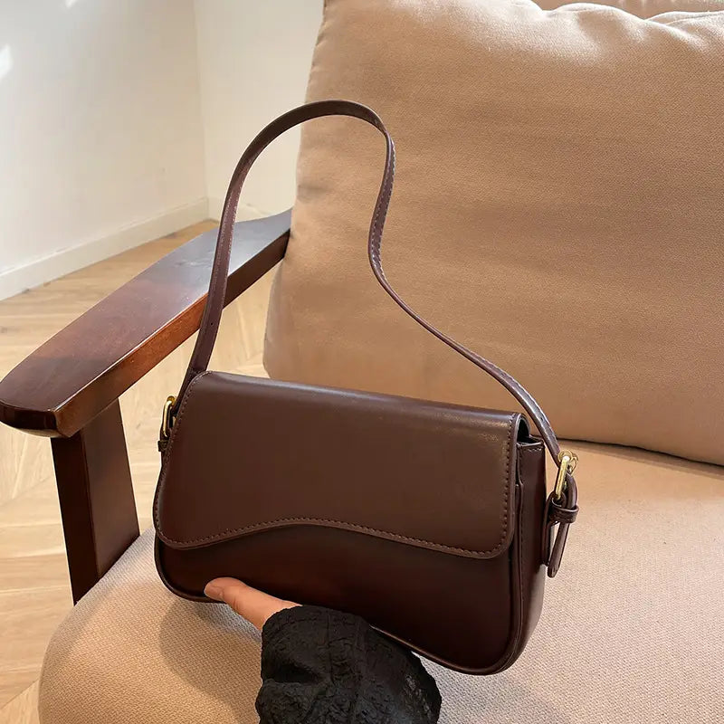Brown leather messenger bag with minimalist crossbody design and gold tone hardware for organized daily use.