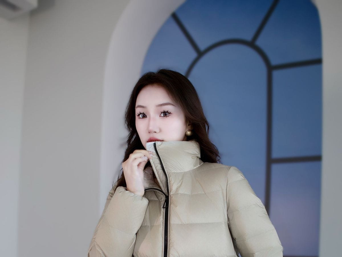 Beige kurze Steppjacke aus Daunen für Damen mit Puffer-Design und schwarzem Reißverschluss, ideal für den Winter.