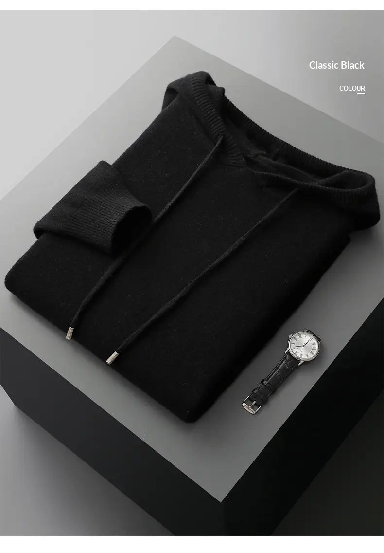 Sudadera con capucha de cachemir negra clásica para hombre, con puños acanalados y cordones, doblada con esmero sobre una superficie de exhibición para uso en invierno.