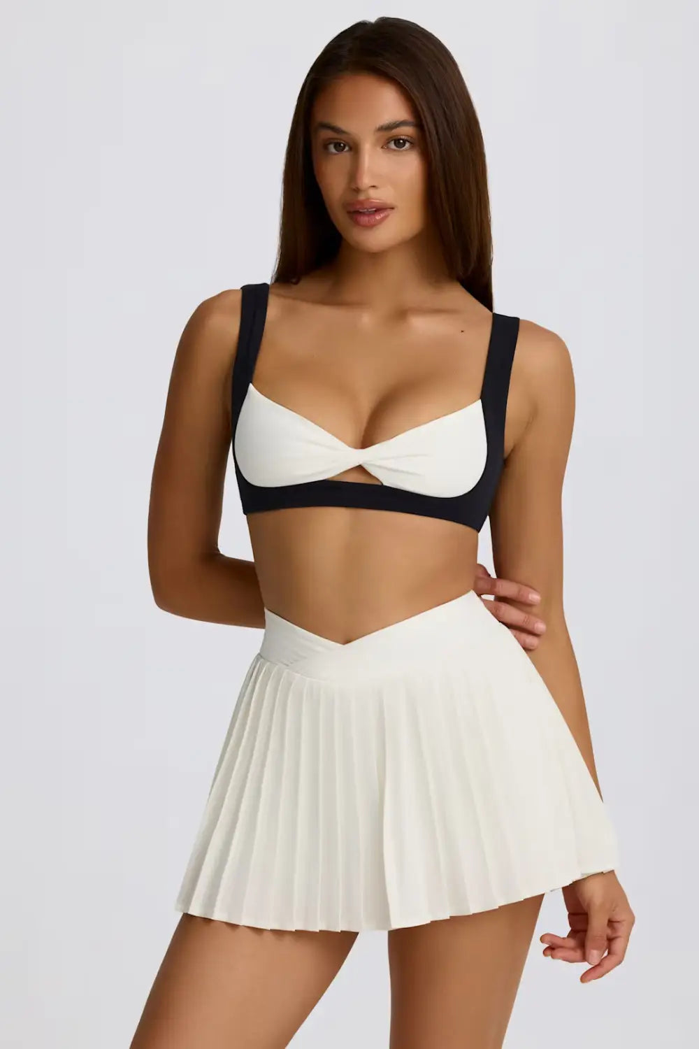 Weißer plissierter Sportrock-Skort mit figurformender Passform und High-Waist-Design, kombiniert mit einem schwarzen Träger-Top zur Fitness-Nutzung