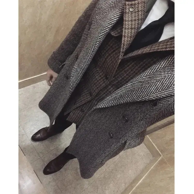 A double-breasted british vintage woolen coat with a slim tweed blazer fit featuring a herringbone pattern in shades of brown and gray.
