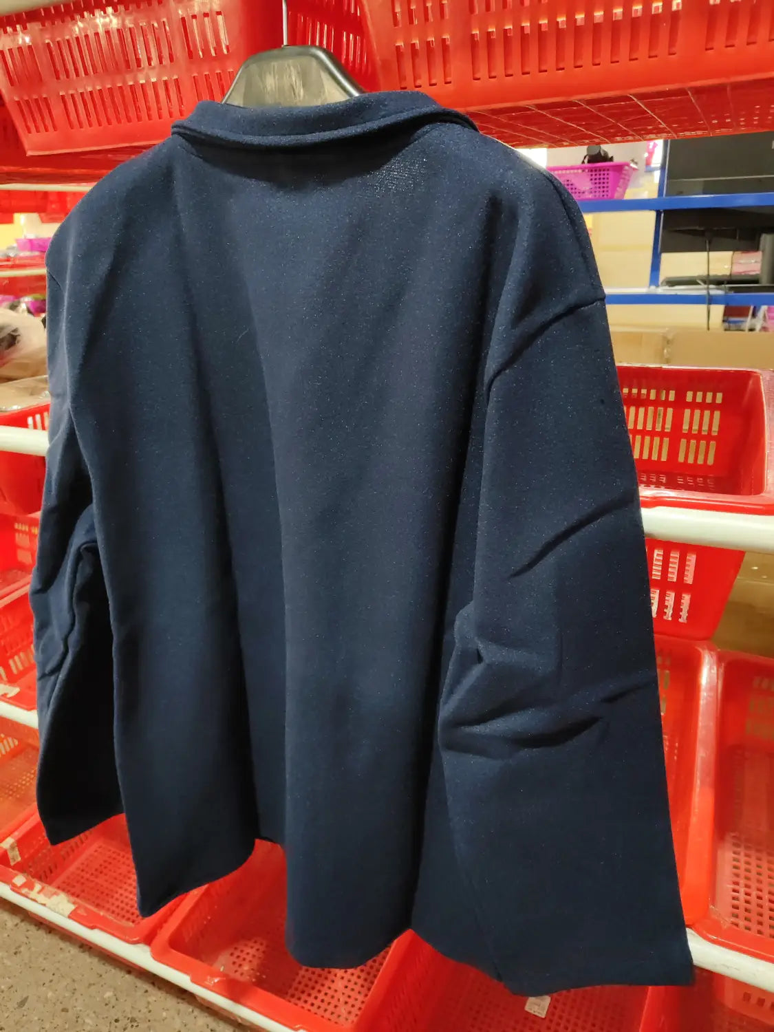 Dark navy blue woolen men hip hop bomber jacket with classic collar and long sleeves displayed on a hanger in a retail setting.