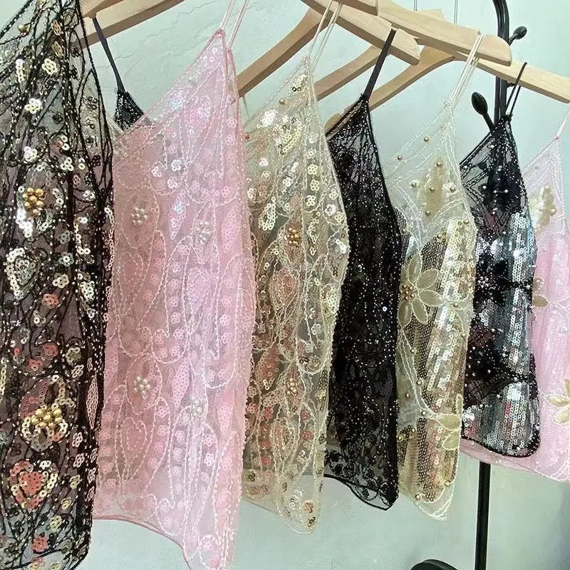 Eine Auswahl an Pailletten-gestickten Mesh-Camisole-Tops in Pink, Schwarz und Gold mit zartem, transparentem Spitzengewebe und Perlenverzierungen.