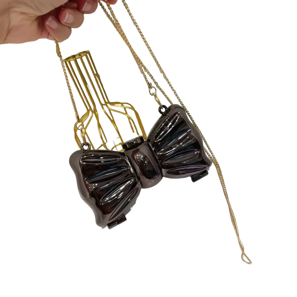 A glossy black acrylic bow crossbody bag clutch with a gold chain strap in metallic gold and silver accents