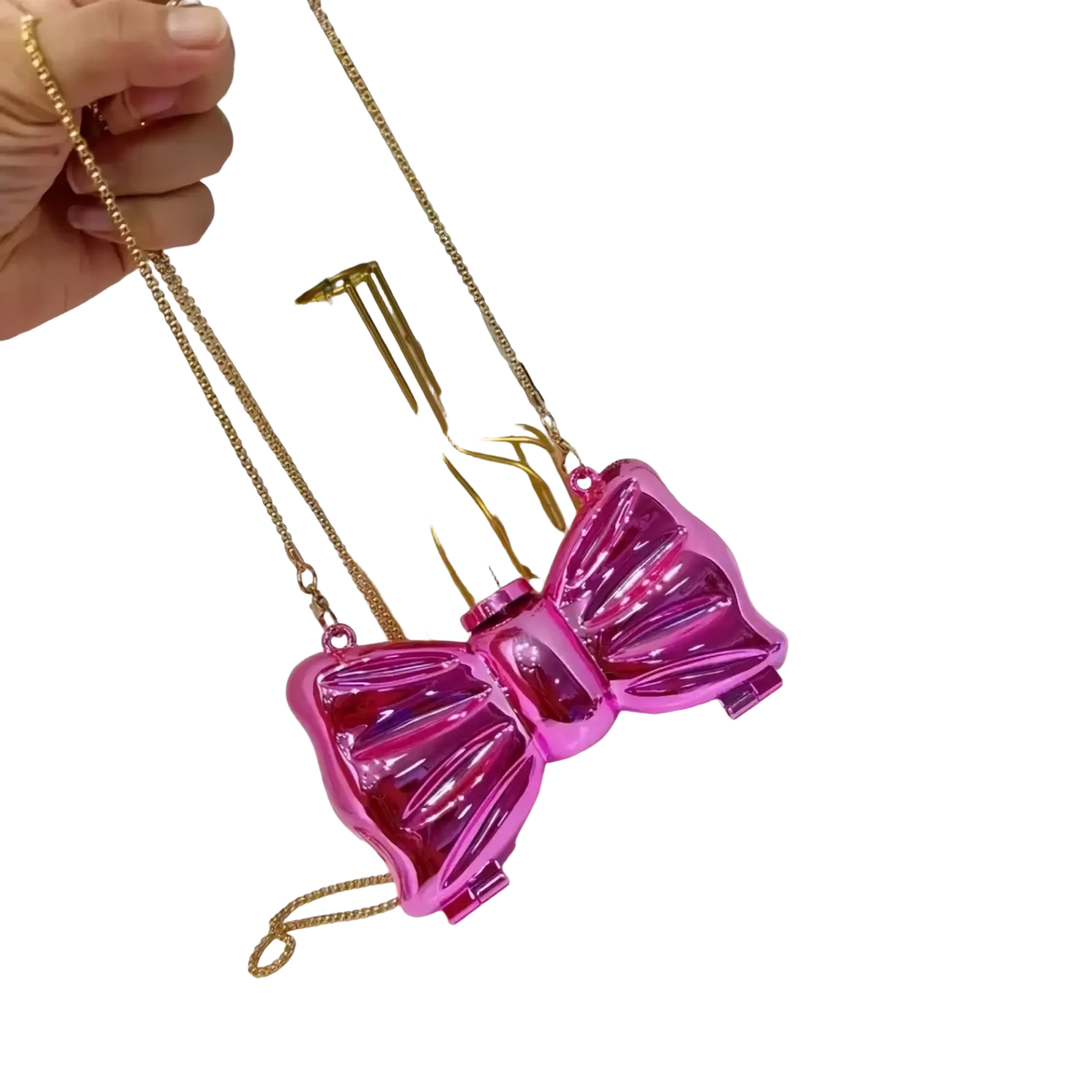 A shiny vibrant pink acrylic bow crossbody bag with a gold chain strap in metallic gold silver clutch style