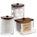 Set of three clear acrylic q-tip and cotton ball storage jars with dark wood lids for bathroom organization