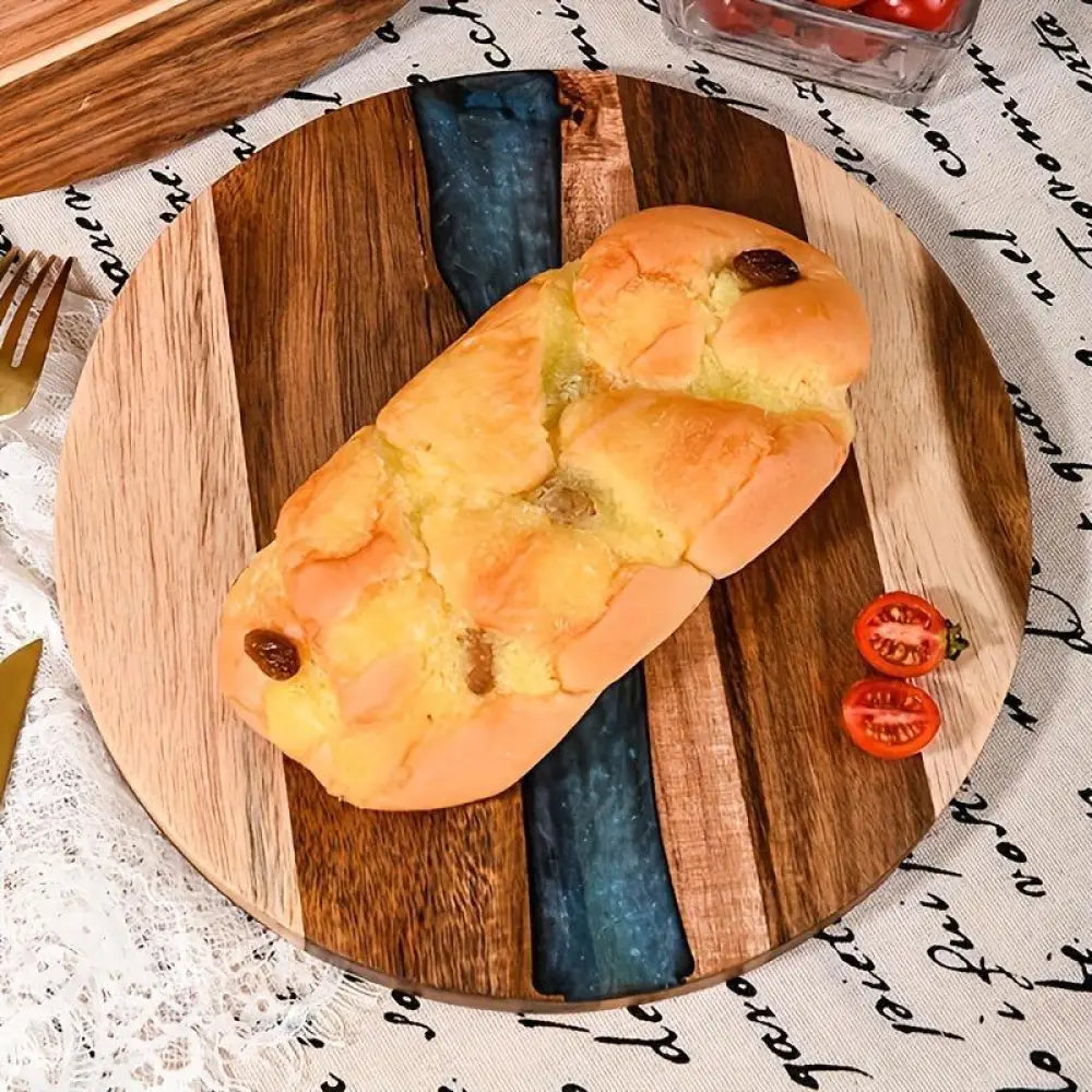 Golden-brown braided bread with raisins on a teal resin river round wooden charcuterie board with rustic finish