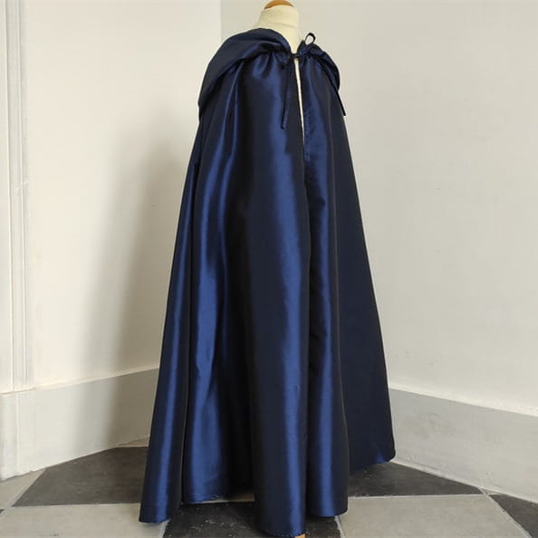 a deep navy satin cape with a hood and front tie closure displayed alongside a wooden cat tree scratching post and condo for pet activity and comfort