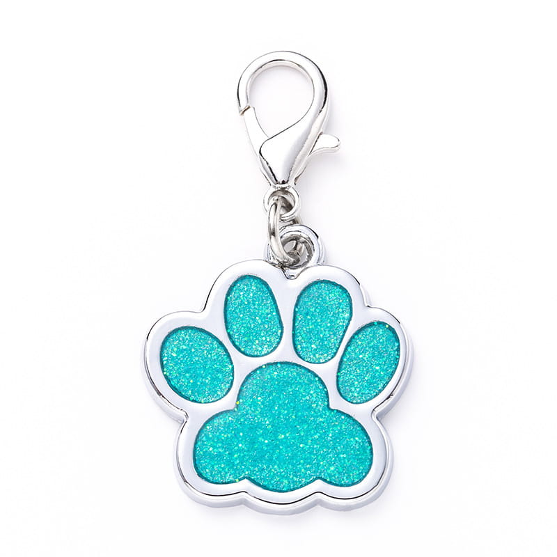 A shiny silver glitter paw print metal dog tag charm with glittery turquoise enamel fill and a lobster clasp.
