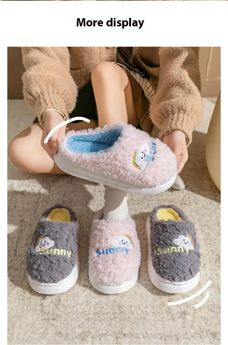 pink fluffy plush cotton slipper with a blue interior and a smiling cloud and rainbow embroidered design.