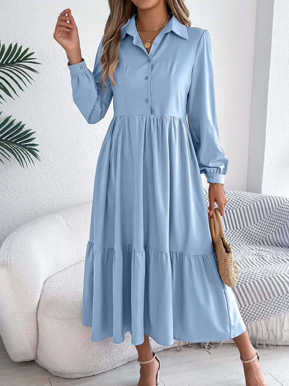 A light blue long sleeve tiered button down midi dress with elastic cuffs and a flowy skirt suitable for women’s casual or semi-formal wear.