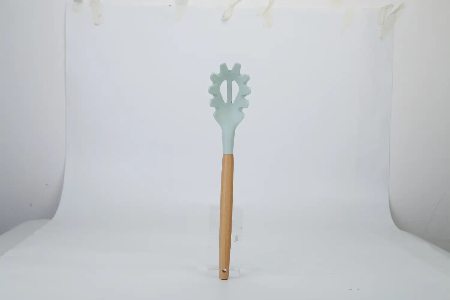 A light blue silicone spatula with a wooden handle and gear-shaped head from an 11-piece silicone cooking utensil set with wood handles.
