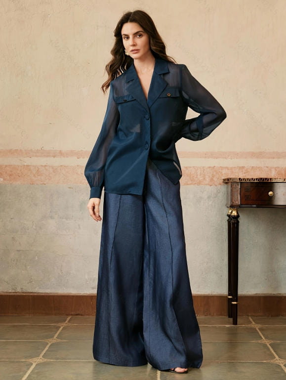 A navy blue satin high waisted wide leg trousers set featuring a blazer with sheer long sleeves and a buttoned front.