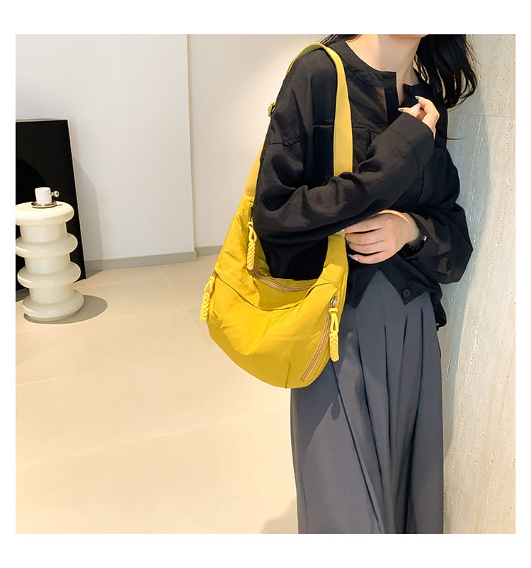 Bright yellow nylon crossbody bag with large capacity featuring braided strap and zipper details for versatile shoulder use.
