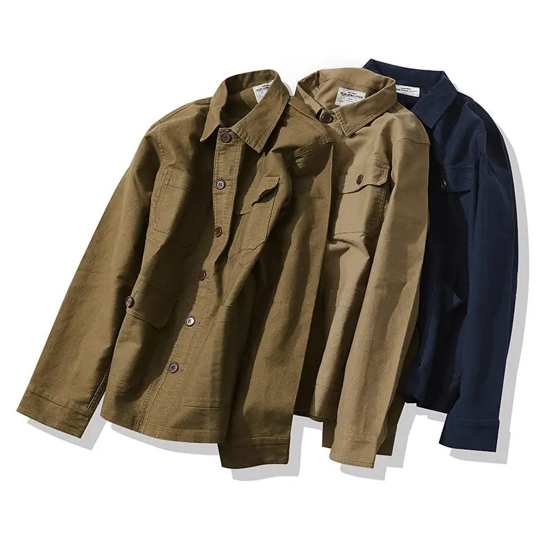 Two olive green and navy blue mens French workwear jacket cotton utility pocket coats with chest pockets made of durable cotton fabric.