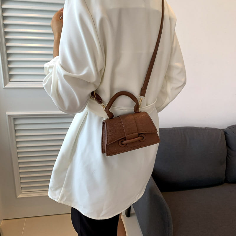 Braune Mini-Handtasche aus Leder mit geformter rechteckiger Form und oberem Tragegriff, vorgestellt in der Kollektion der Ketten-Umhängetasche Mini aus Kunstleder.