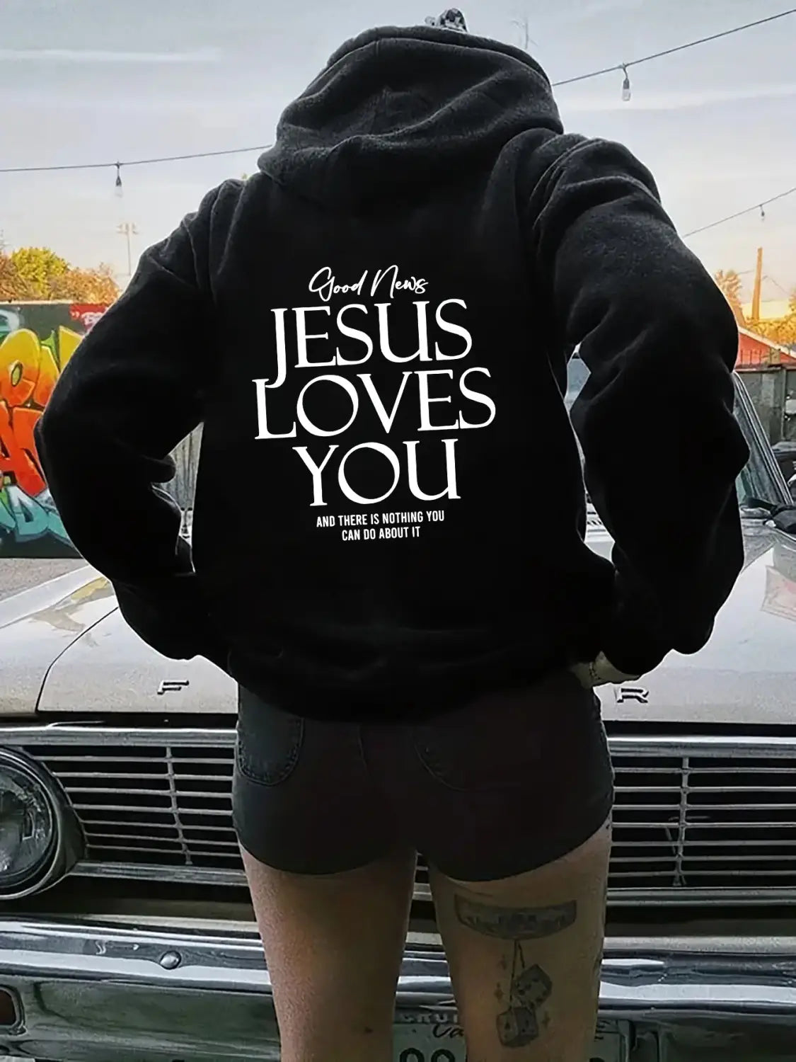 black oversized streetwear hoodie with kangaroo pocket featuring white text reading good news jesus loves you and there is nothing you can do about it on the back