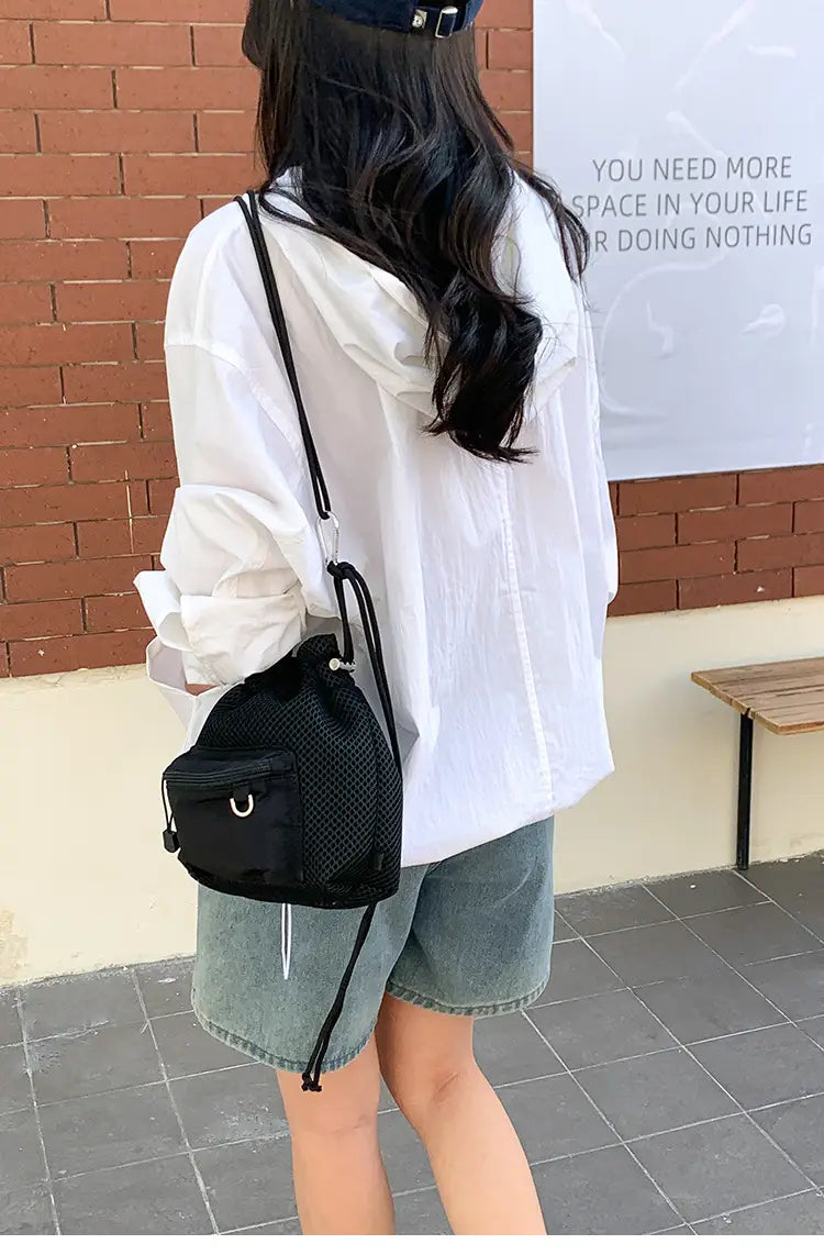 Black mesh drawstring bucket bag with small front pocket and silver-toned metal ring detail in mini pink mesh design with heart charm.