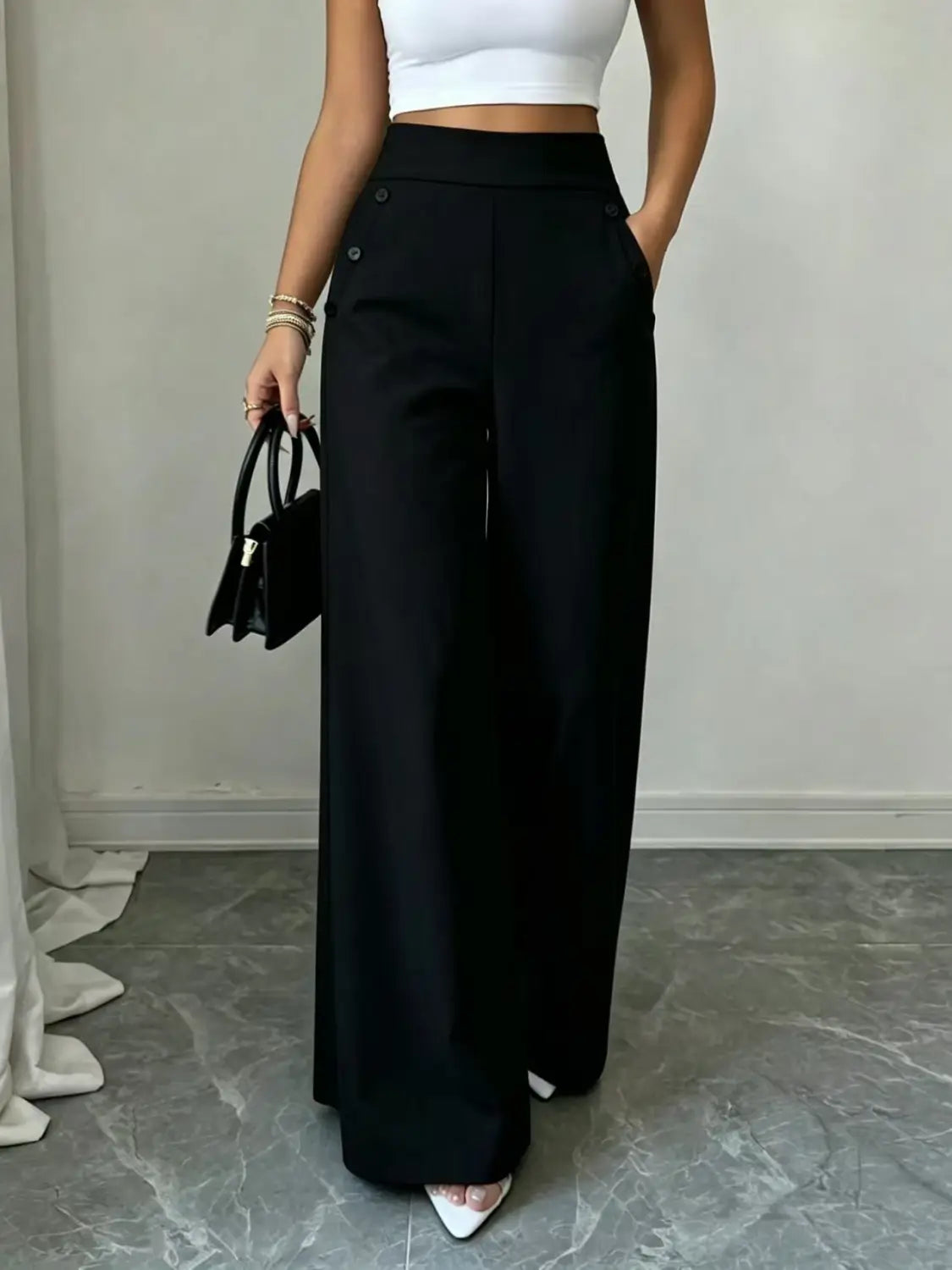 Pantalon ample taille haute noir avec coupe ajustée et soignée, ainsi que des détails de boutons sur le côté.