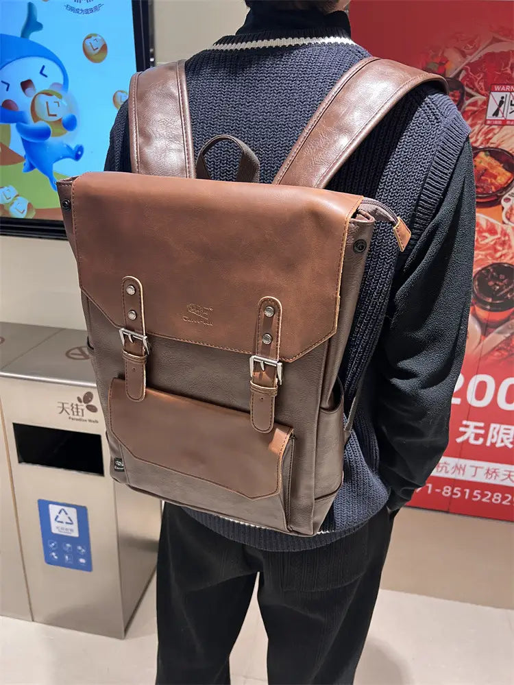 Vintage leather college backpack in brown with two-tone design featuring darker brown straps and lighter tan front panels accented by silver-toned metal buckles for large capacity travel use.
