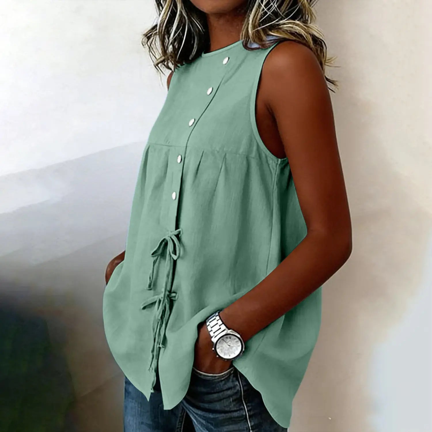 A soft sage green sleeveless tie side button down blouse featuring a button front and waist tie detail.