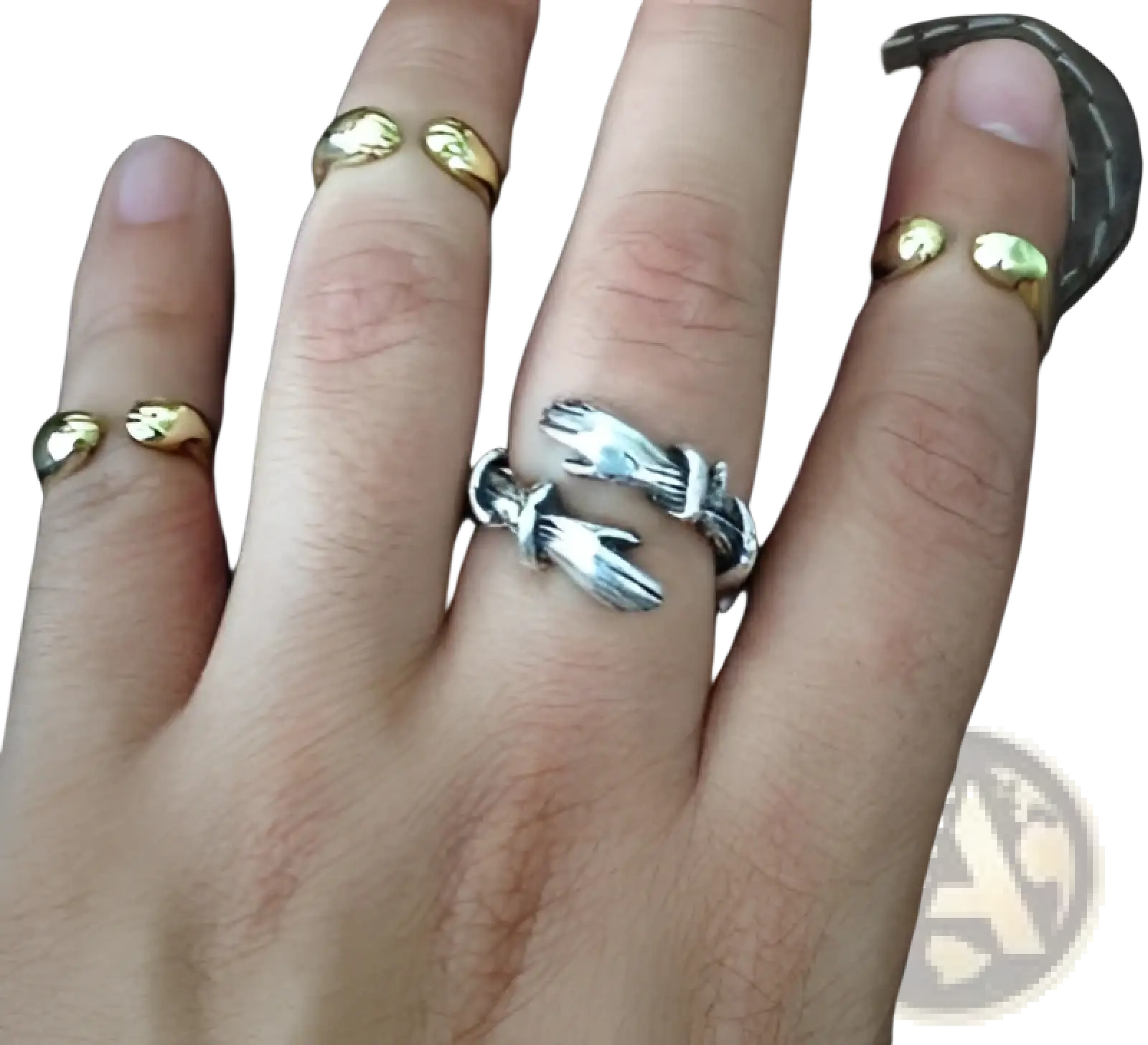 Adjustable silver and gold hand-clasped ring with detailed texture and red gemstone worn on the middle finger