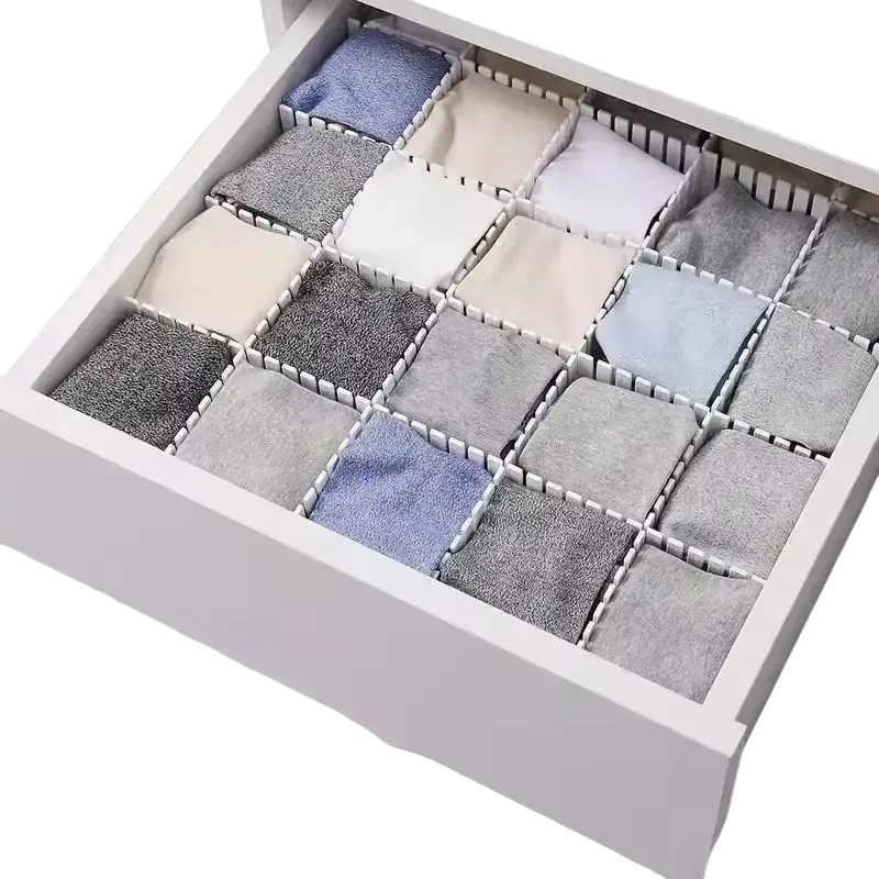 Adjustable white plastic drawer divider partition with interlocking grid compartments organizing socks in various shades