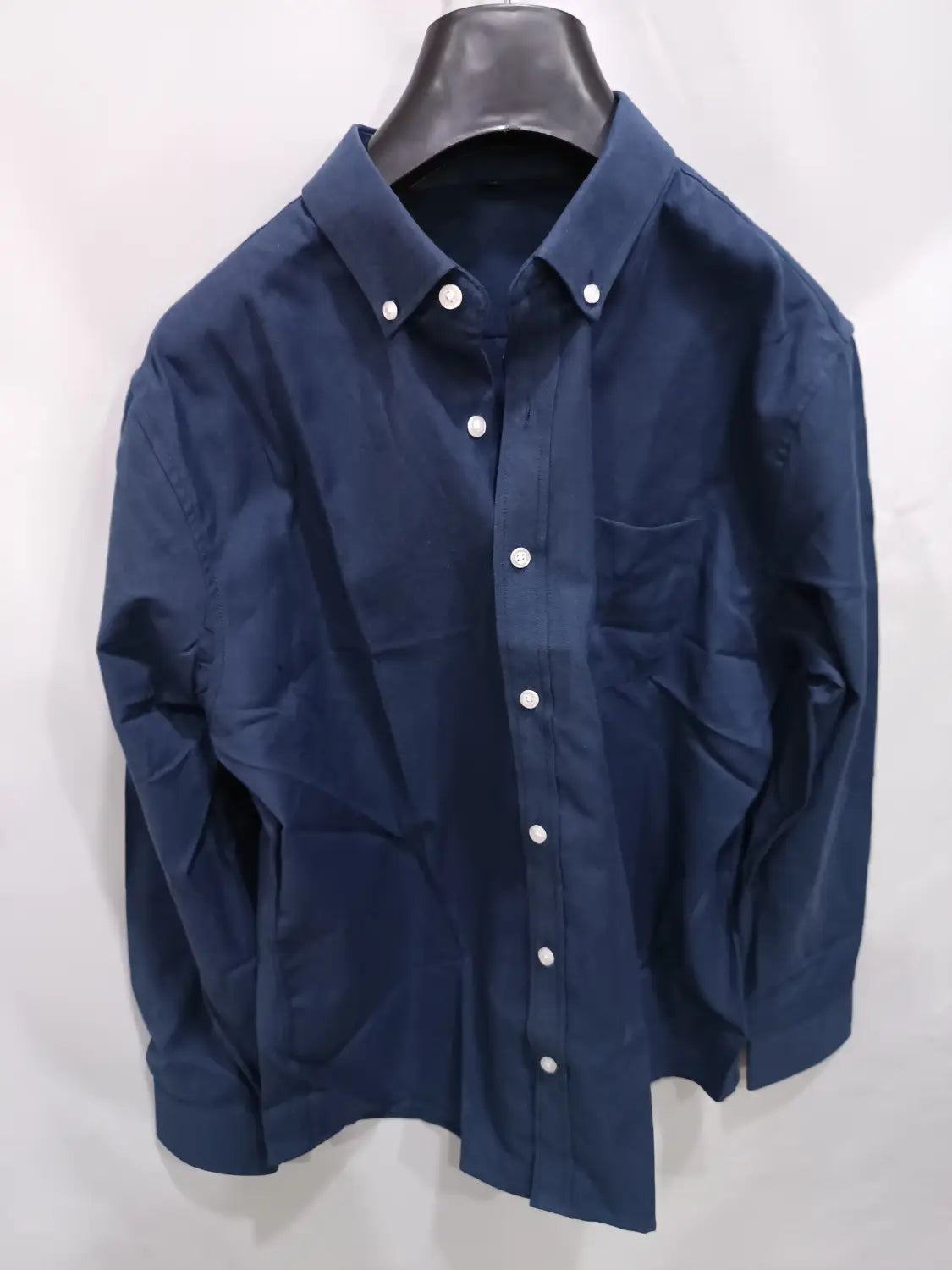 Dunkelblaues Herren-Oxford-Freizeithemd aus reinem Baumwoll-Mischgewebe in Uni-Farbe mit langen Ärmeln, weißen Knöpfen und einer Brusttasche.