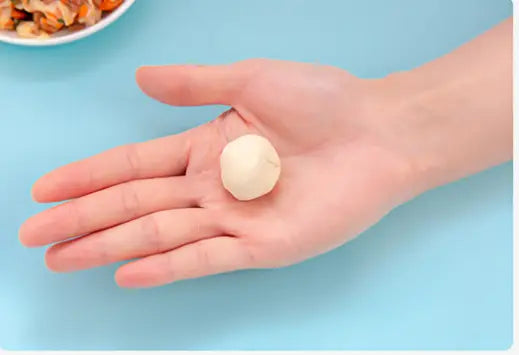 a pale, smooth ball of dough resting in the palm next to a dumpling maker 3 in 1 manual dough pressing tool designed for efficient dough shaping and pressing