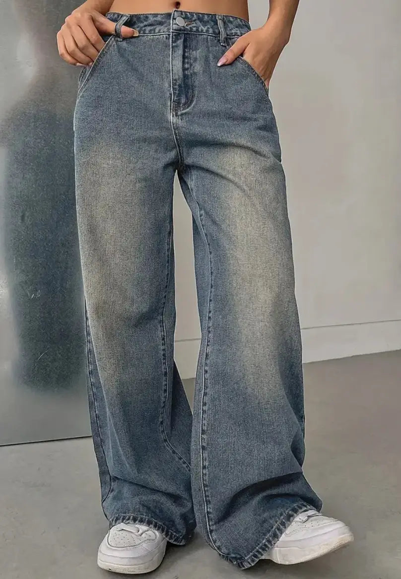 Jeans en denim vintage délavé à jambes larges en délavage bleu délavé, avec un léger effet vieilli et des finitions d’ourlet brut.