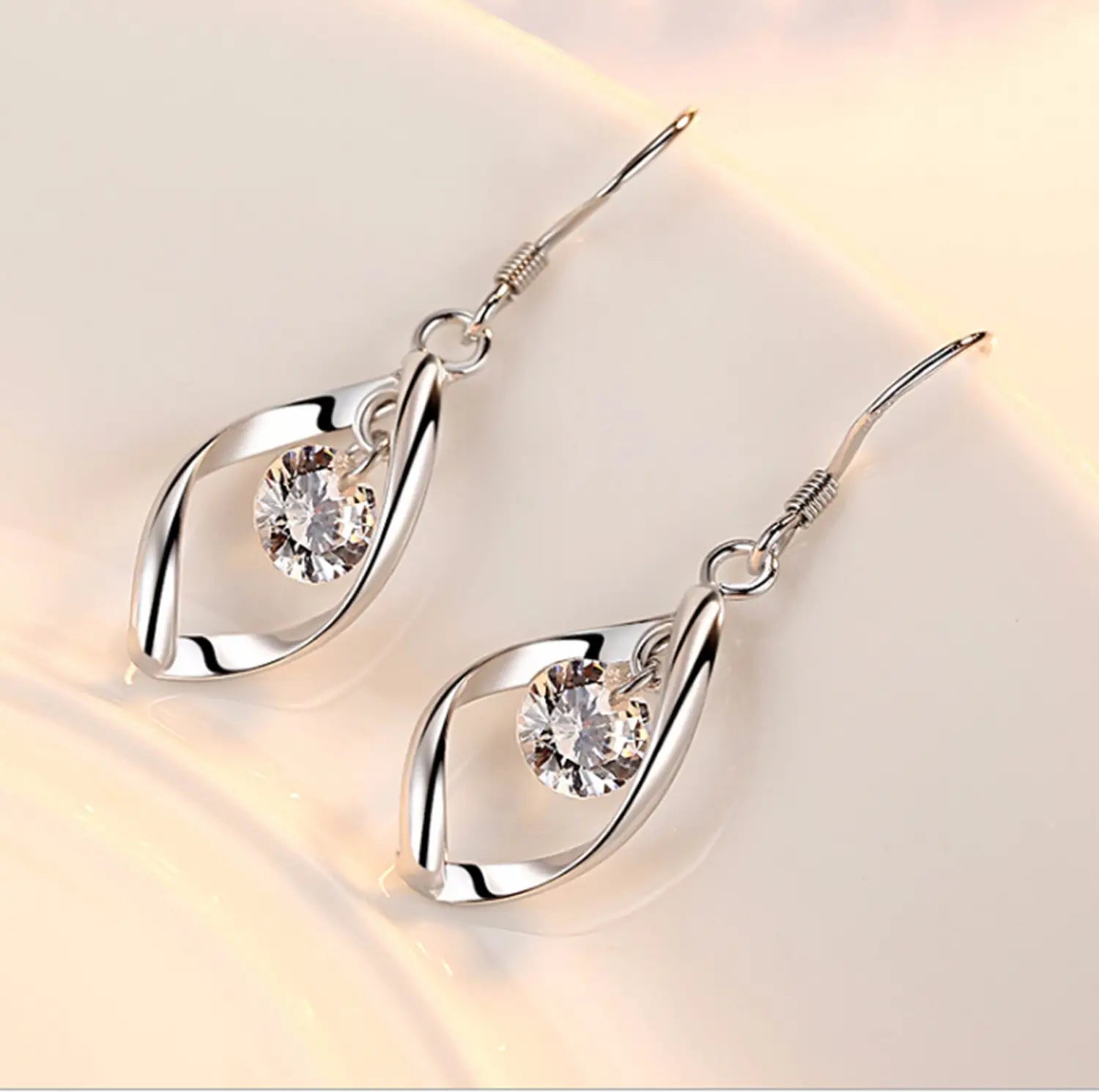 twisted teardrop silver earrings feature a twisted leaf-like design with a clear faceted crystal center.