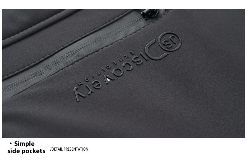 Mochila negra con marca Discovery Expedition, con logotipo sutil en relieve y detalle de la cremallera mostrado desde el lado posterior de un abrigo de invierno acolchado con capucha para hombre.