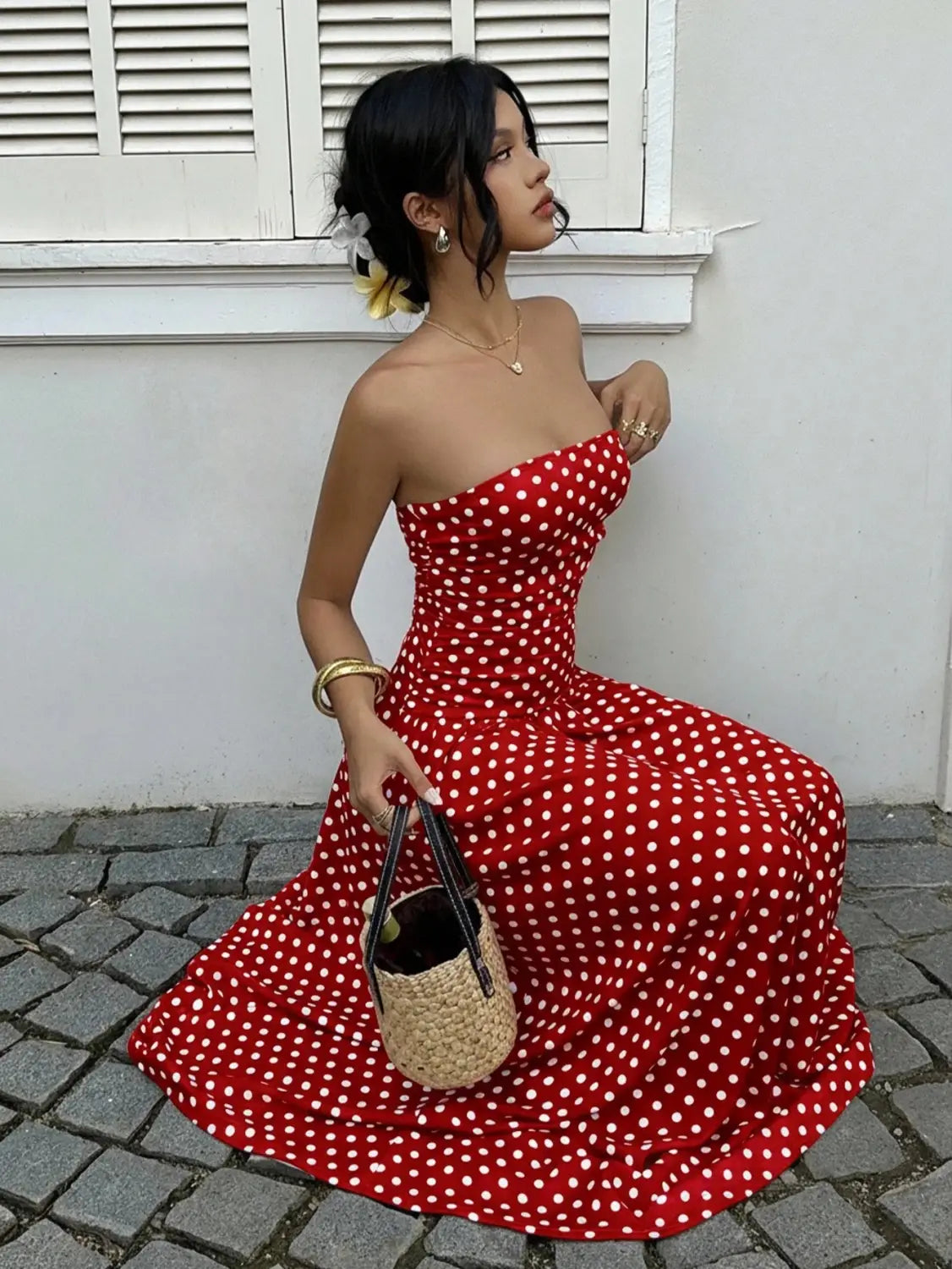 Red strapless maxi dress with white polka dots made of flowing fabric featuring an off shoulder design.