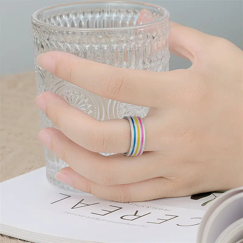 A colorful striped rainbow enamel inlay stainless steel unisex band ring with multiple bands worn on a finger.